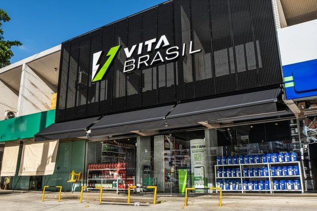 Fachada de outra loja VitaBrasil, com expositores de suplementos montados na calçada.